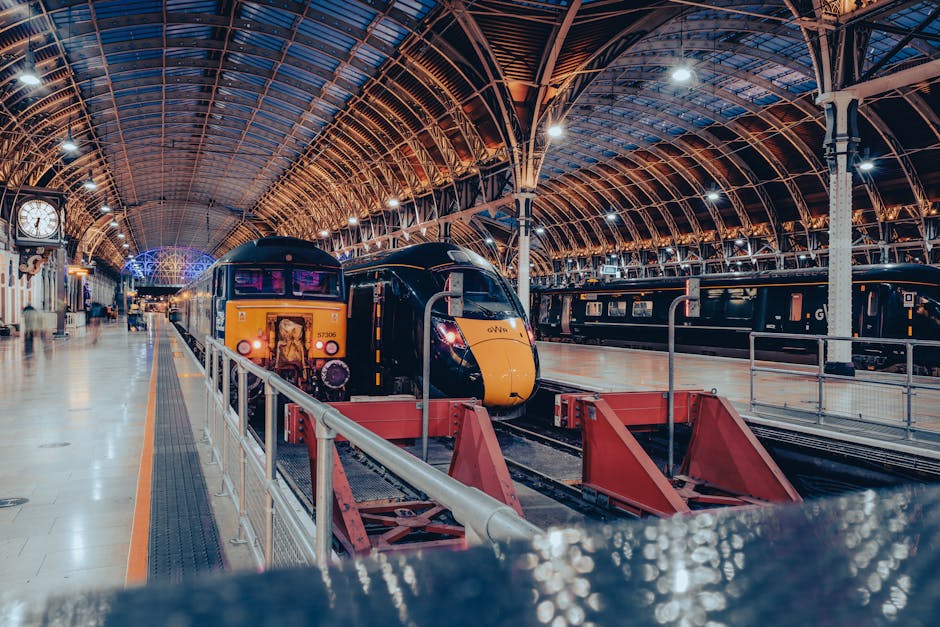 The image displays the intricate interior roof of a large train station with a curved, vaulted structure made of metal, glass, and decorative architectural elements. Prominent steel beams with rivets